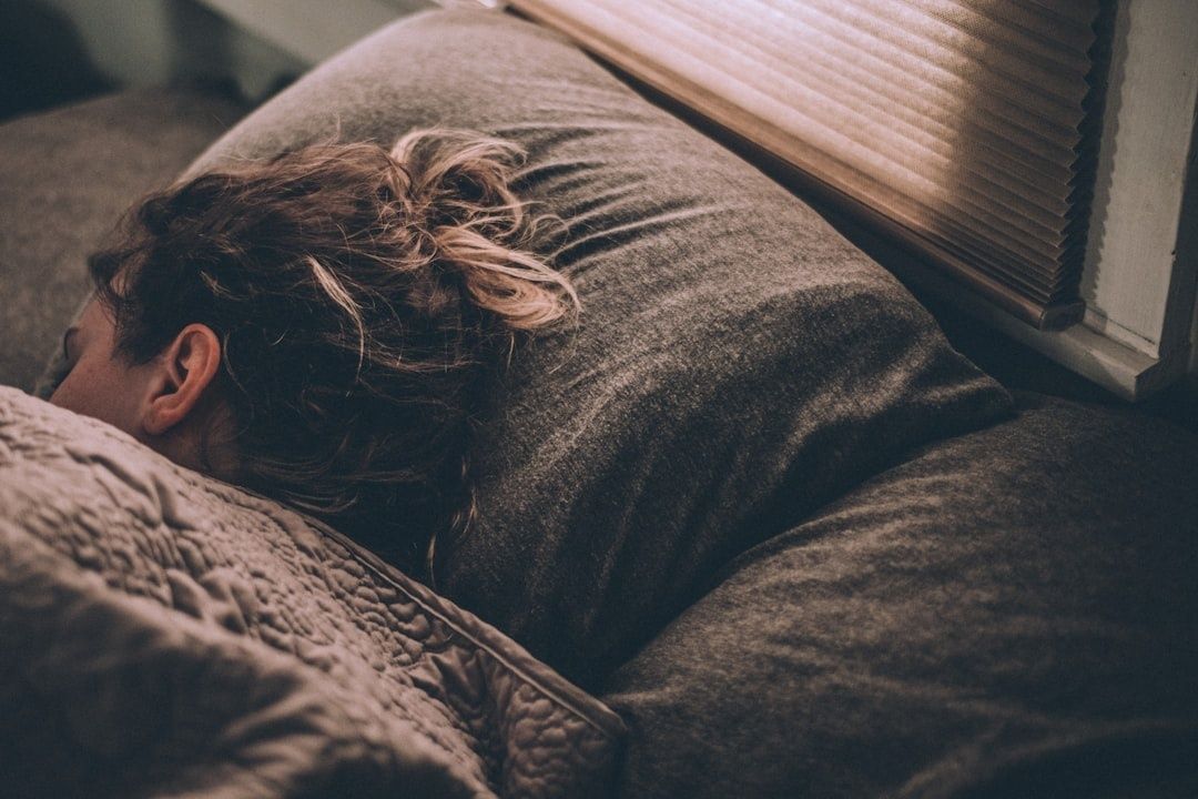 Person som sover under ett täcke i ett mörkt, rofyllt sovrum
